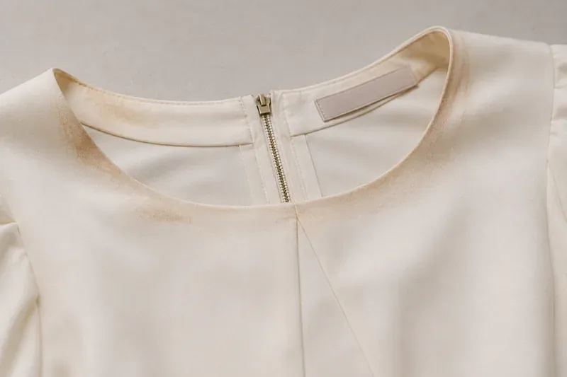 Make-up transfer at the neckline of a pale top.