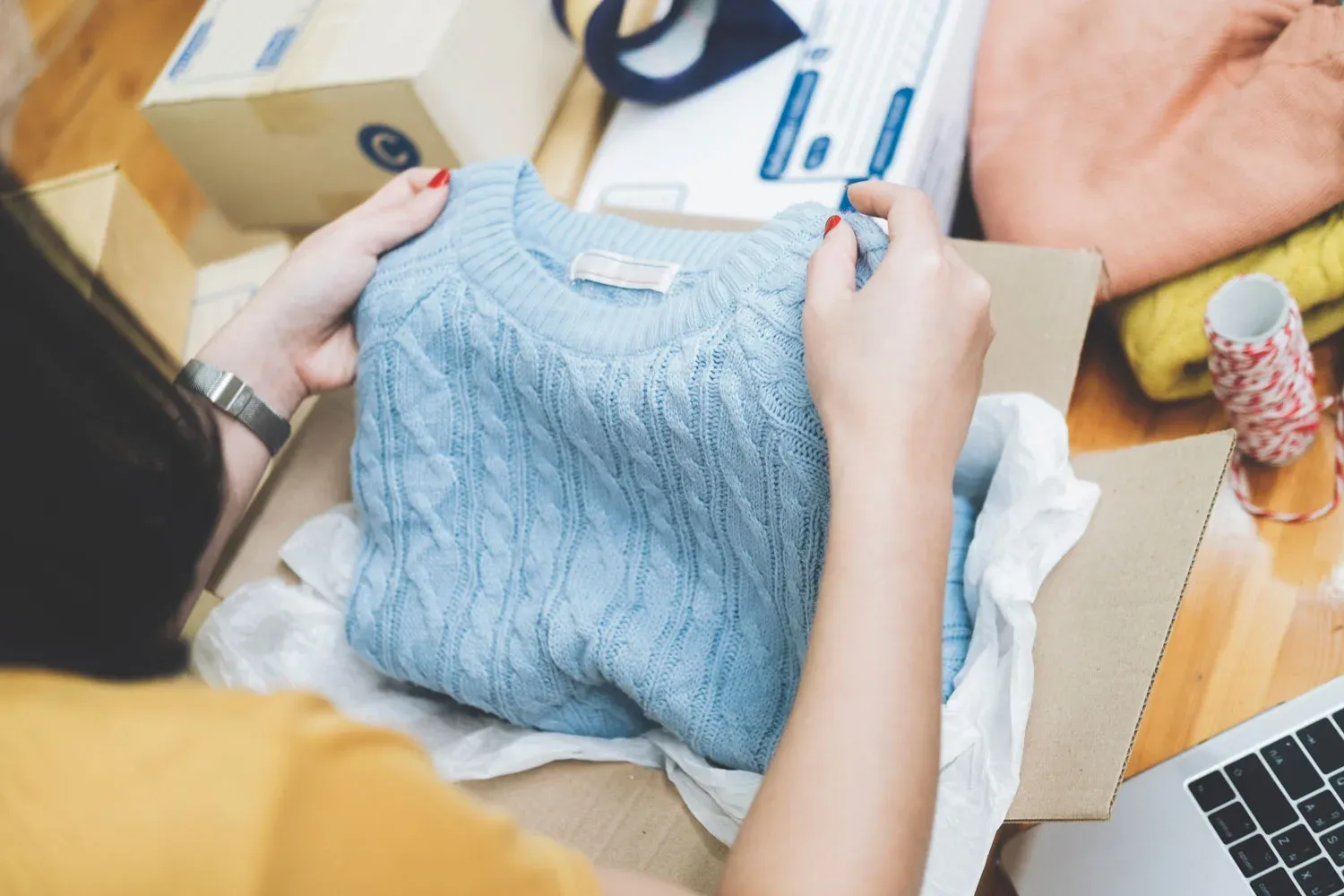 A returned knit being unpacked and logged at a laptop.